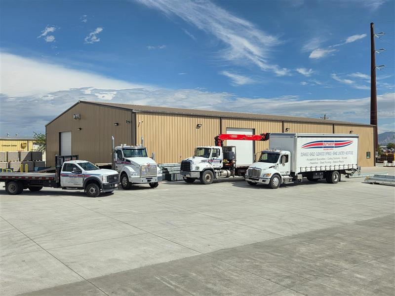 Four Outwest delivery trucks parked outside the Grand Junction yard