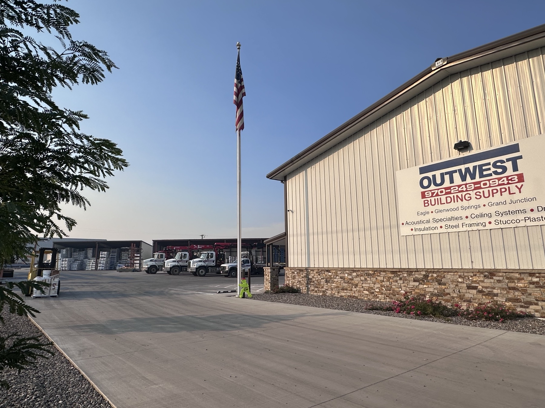 Outwest Montrose building, flagpole, yard, and delivery trucks