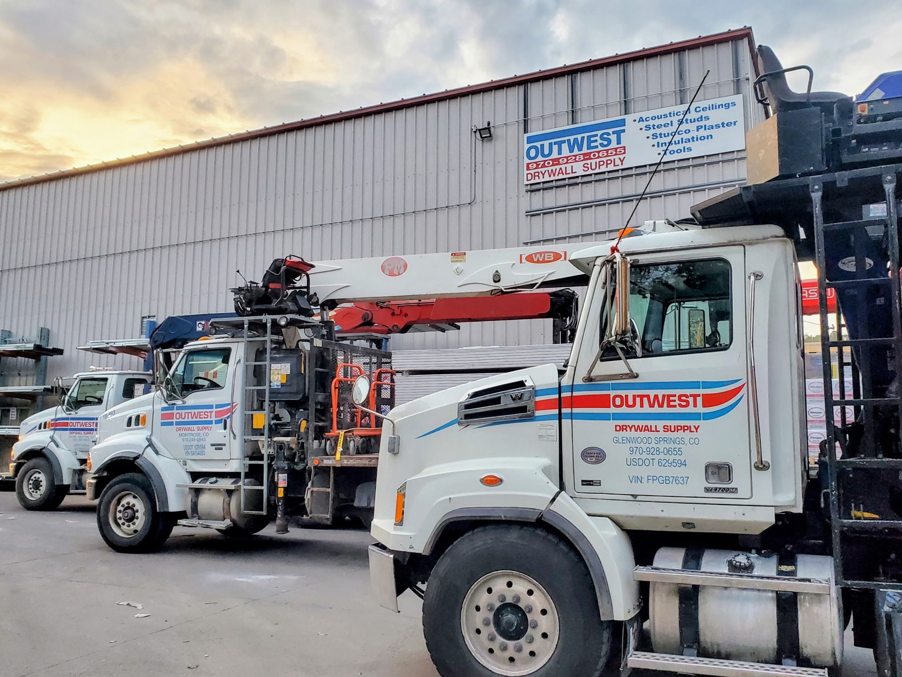 Outwest delivery trucks parked outside a warehouse
