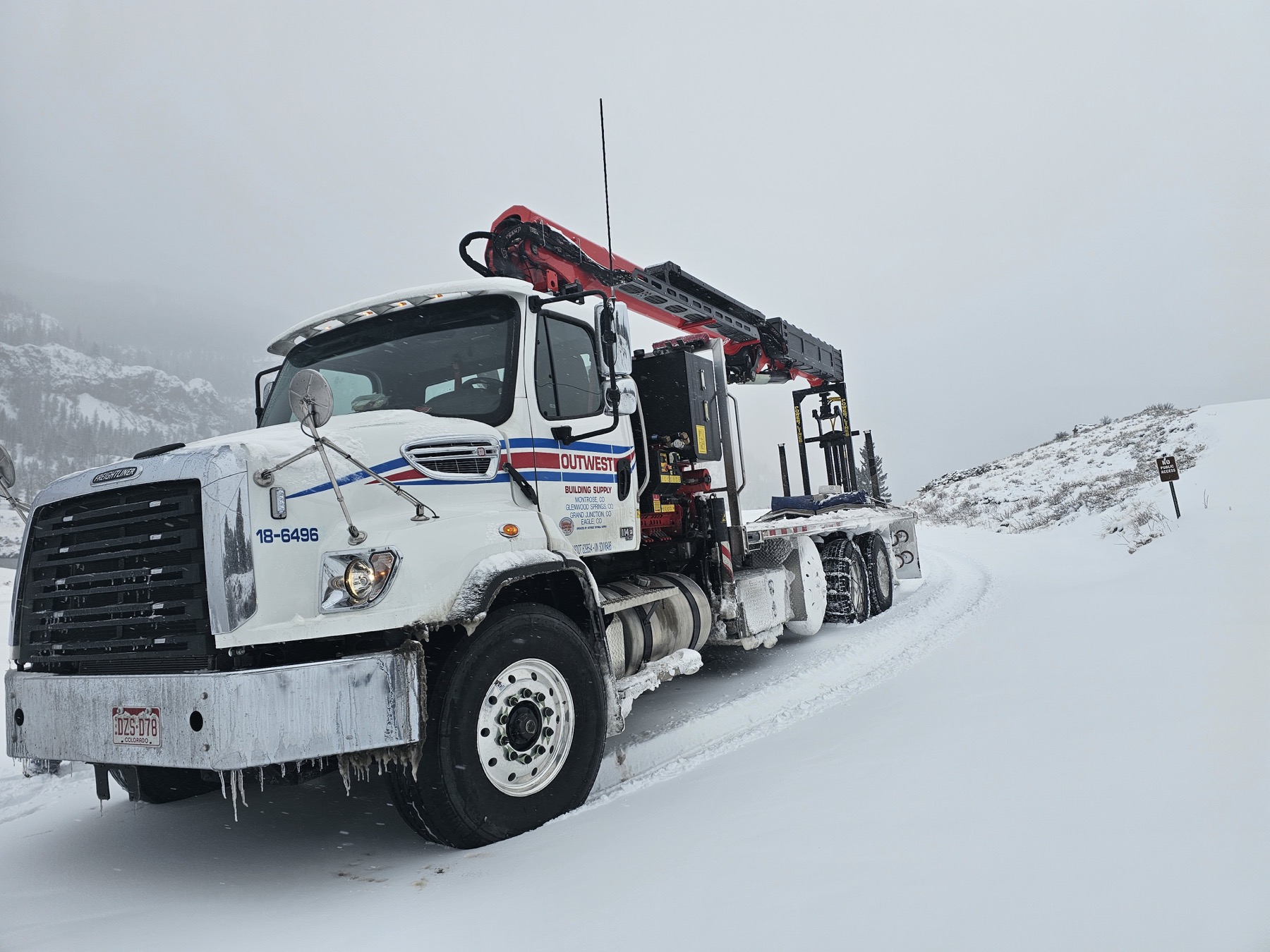 An Outwest boom truck on a snow-covered Colorado road